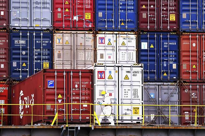 중국 산둥성 칭다오항에서 방호복을 입은 한 직원이 컨테이너가 적재된 선박 옆을 지나가고 있다. / AP 연합뉴스