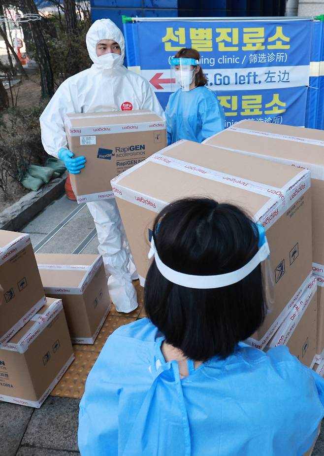서울 동작구 보건소 관계자들이 28일 코로나19 자가검사키트를 보관 장소로 옮기고 있다. 29일부터 전국 보건소, 대형병원 코로나19 선별진료소는 유전자증폭(PCR) 검사와 신속항원검사를 병행 실시한다. 연합뉴스