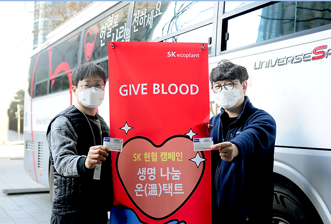 헌혈 버스에서 헌혈에 동참한 직원들이 헌혈증서를 들고 웃고 있다. [사진 = SK에코플랜트]