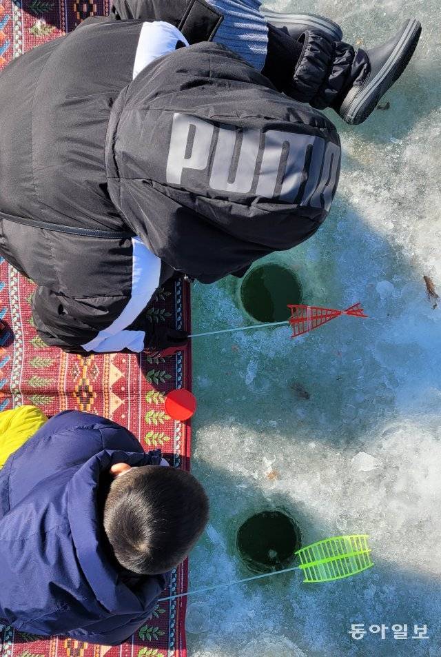 얼음에 구멍을 뚫고 빙어가 잡히길 기다리고 있는 한 가족.