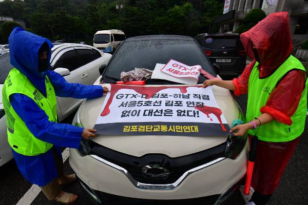 정부가 수도권광역급행철도(GTX) D노선을 경기도 김포에서 부천종합운동장까지만 연결하기로 하자 이에 반발하는 김포 주민들이 지난해 7월 4일 김포시청에 모여 GTX-D의 하남 직결을 요구하는 스티커를 차량에 부착하고 있다. 여야 대선 후보들이 GTX-D노선 개편을 공약하면서 3월 대선 이후에는 김포에서 하남까지 연결되는 노선으로 개편이 추진될 것으로 보인다.   최현규 기자