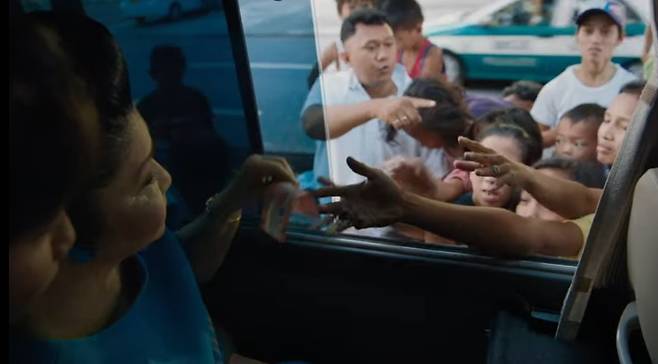 지나는 곳마다 지갑을 열어 거리의 시민들에게 돈을 나눠주는 이멜다. 다큐멘터리 ‘더 킹메이커 2019’중 한장면