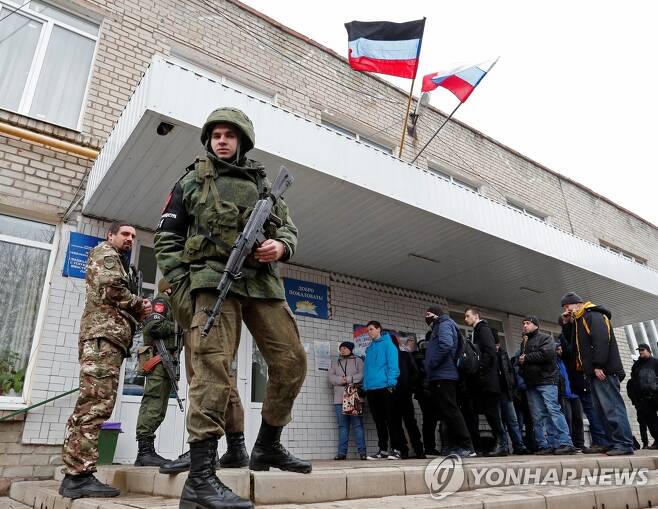 친러 반군 동원령에 응하는 우크라이나 도네츠크 남성들 (도네츠크 로이터=연합뉴스) 23일(현지시간) 우크라이나 동부 도네츠크의 한 모병소에 친(親)러시아 반군 조직이 세운 도네츠크인민공화국(DPR)의 동원령에 따라 소집된 남성들이 모여 있다. 건물 위에는 DPR 깃발이 펄럭이고 그 앞에는 반군 병사가 총을 들고 서 있다. DPR와 인근 루간스크인민공화국(LPR)은 18∼55세 남성에게 총동원령을 내렸다. 2022.2.24 sungok@yna.co.kr