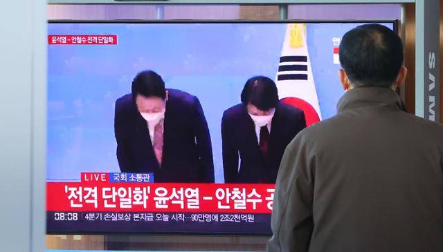 제20대 대선 사전투표를 하루 앞둔 3일 오전 사전투표소가 마련된 서울역 대합실 인근에 설치된 TV화면에 국민의힘 윤석열- 국민의당 안철수 후보 단일화 기자회견이 중계되고 있다. 연합뉴스