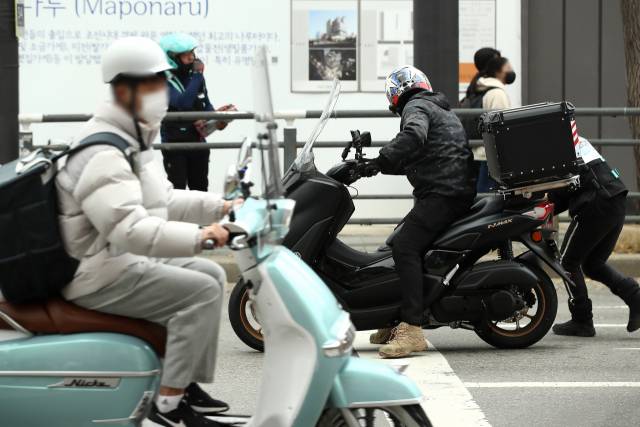 ▲민주노총 배달플랫폼지부 조합원들이 19일 서울 마포구 홍대입구 사거리에서 '정지선 지키기 캠페인'의 일환으로 배달노동자들에게 겨울용 장갑과 생수, 마스크 등을 전달하고 있다. ⓒ연합뉴스