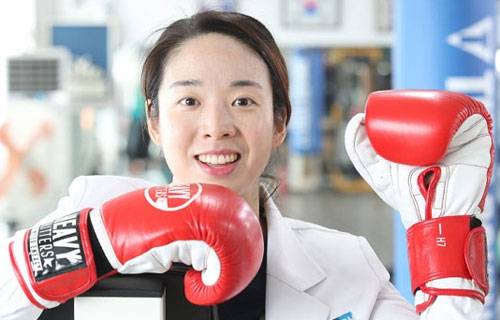 서려경 삼성서울병원 전임의는 낮에는 신생아 중환자를 돌보고 저녁에는 체육관에서 샌드백을 때리는 생활을 해왔다. 서씨가 천안시 BEAT 손정오복싱클럽에서 가운을 입고 글러브를 낀 채 웃고 있다. [이충우 기자]