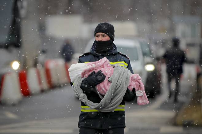 우크라이나와 루마니아의 국경 지역인 시레트에서 3월 7일 한 소방관이 피란 중인 아기를 안고 있다.  AP연합뉴스