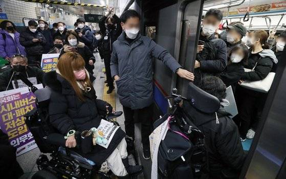 전국장애인철폐연대 활동가들이 지난해 12월 9일 오전 서울 종로구 혜화역 승강장에서 교통약자 이동편의 증진법 연내 개정을 촉구하는 선전전을 마친 뒤 전철에 타고 있다. [뉴시스]
