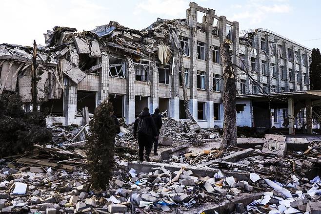 우크라이나 서부 지토미르에서 러시아군 공습에 파괴된 건물 앞을 시민들이 지나고 있다. EPA 연합뉴스