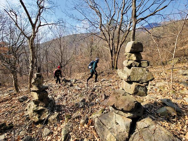 자굴산 절터샘으로 향하는 남릉. 아슬아슬한 돌탑 너머로 자굴산 정상에서 자굴티재로 흐르는 진양기맥이 하늘금을 이룬다.