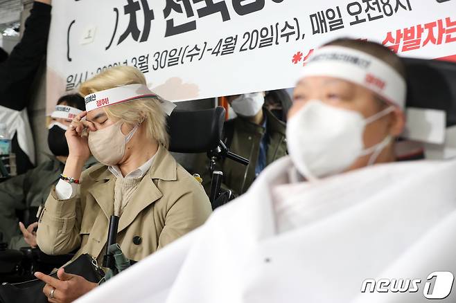 30일 오전 서울 종로구 지하철3호선 경복궁역 승강장에서 열린 '장애인권리예산 인수위 답변 촉구를 위한 전국장애인차별철폐연대 삭발 투쟁 결의식'에서 전장연 회원이 이형숙 서울시장애인자립생활센터 회장의 삭발식을 지켜보며 눈물을 흘리고 있다. 2022.3.30/뉴스1 © News1 황기선 기자