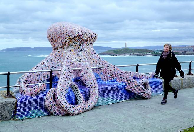 해안산책길의 대형 문어 타일작품과 즐겁게 걷기여행하는 스페인 아줌마.