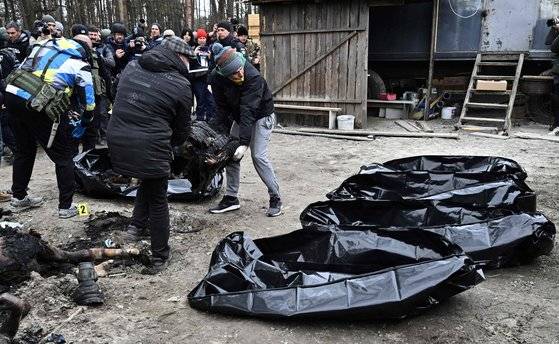 지난 5일(현지시간) 우크라이나 수도 키이우 인근 도시 부차에서 경찰과 시 당국 직원이 불탄 시신을 옮기는 모습. Genya SAVILOV / AFP. 연합뉴스.