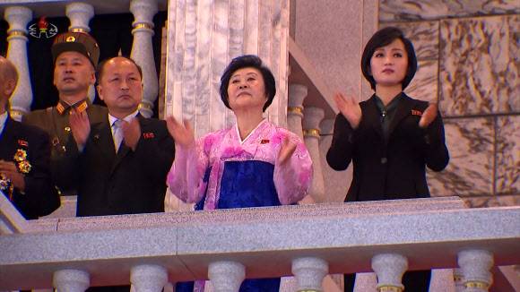 손뼉치며 열병식 행사 지켜보는 리춘히와 김옥주 - 한복을 입은 리춘히 아나운서와 ‘인민배우’ 칭호를 받은 가수 김옥주가 손뼉을 치며 행사를 지켜보고 있다. 리 아나운서는 녹화 중계된 이날 행사의 TV 방송 해설을 맡기도 했다. 조선중앙TV 화면 2021.9.9