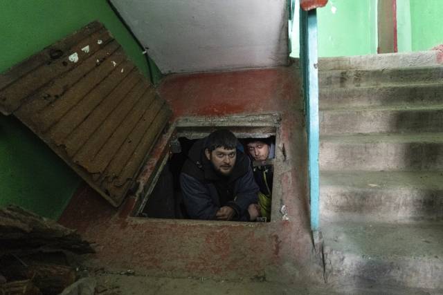 우크라이나 마리우폴 시민들이 지난달 12일 한 건물 지하에 임시방편으로 만든 간이 방공호에 숨어 작은 출입구로 조심스럽게 밖을 내다보고 있다. AP뉴시스