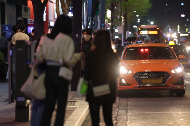 코로나19 방역을 위한 사회적 거리두기가 전면 해제된 18일 자정을 넘긴 시간 서울 강남역 인근에서 시민들이 택시를 잡기 위해 서 있다. 연합뉴스