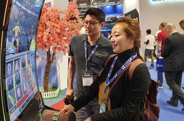 ▲지난 2019년 5월 21일 마카오 베네시안에서 열리고 있는 G2E ASIA 행사의 강원랜드 부스를 방문한 참관인들이 사베리 슬롯머신을 즐기고 있다. ⓒ프레시안