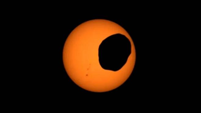 태양면을 가로지르는 화성 위성 포보스를 보여주는 비디오의 스크린샷. NASA의 화성탐사 로버 퍼서비어런스가 2022년 4월 2일 마스트캠-Z 카메라로 비디오를 캡처한 것. 왼쪽에 흑점 그룹도 보인다.ASA/JPL-Caltech 