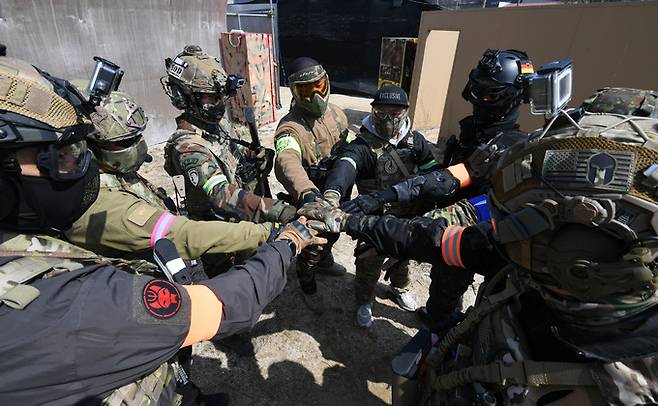 에어소프트 게임에 참가한 동호인들이 시작에 앞서 손을 모으고 파이팅을 외치고 있다.