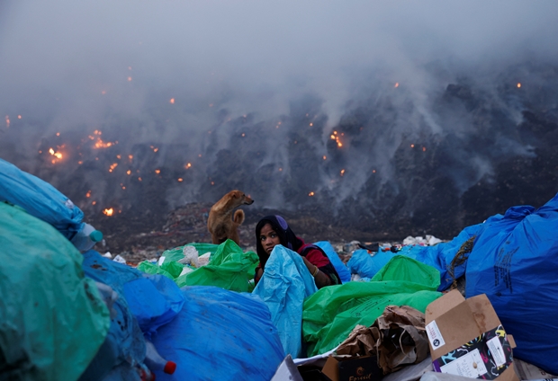 27일(현지시간) 인도 수도 뉴델리 발스와 쓰레기 매립지 화재 현장에서 폐기물 수집가가 쓸만한 쓰레기를 고르고 있다./로이터 연합뉴스