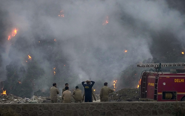 27일(현지시간) 인도 수도 뉴델리 발스와 쓰레기 매립지 화재 현장에 구경꾼이 모여 있다./AP 연합뉴스
