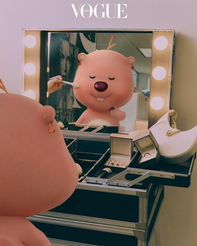 루피의 부캐 잔망 루피가 귀걸이를 착용하고 화장대 앞에 앉아 화장을 받고 있다. 보그 홈페이지