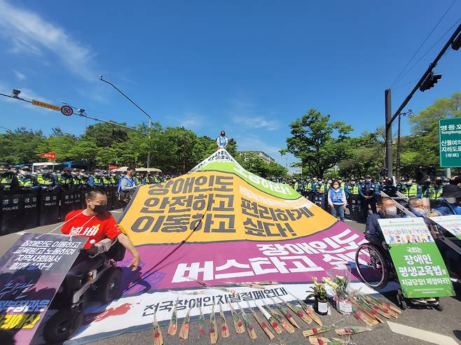 전국장애인차별철폐연대(전장연)가 10일 윤석열 대통령 취임을 맞아 서울 영등포구 여의도공원 앞 도로에서 ‘차별 철폐를 위한 권리선언’ 집회를 열었다. 전장연 등은 윤 대통령 취임을 축하한다는 의미에서 ‘장애인 권리 예산 보장’ 등 문구를 붙인 장미꽃과 화분을 준비했다.