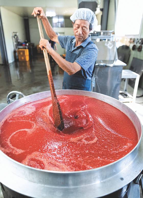 평화나무농장 김준권 대표가 커다란 솥에서 끓고 있는 토마토 주스를 주걱으로 저어주고 있다. 박종근 기자