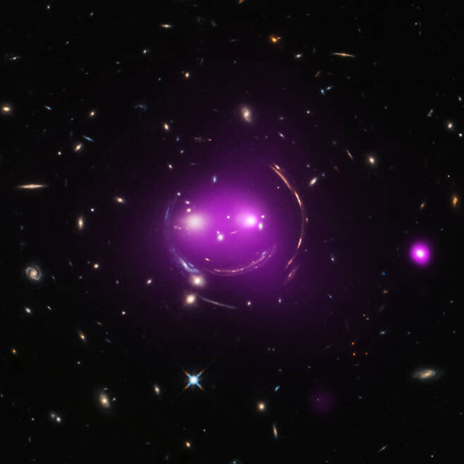 중력 렌즈가 만들어낸 마술, ‘우주의 미소’. 거대한 호는 중력 렌즈 현상에 의해 만들어진 먼 배경 은하의 광학 이미지이다. X-ray - NASA / CXC / J. Irwin et al. ; Optical - NASA/STScI