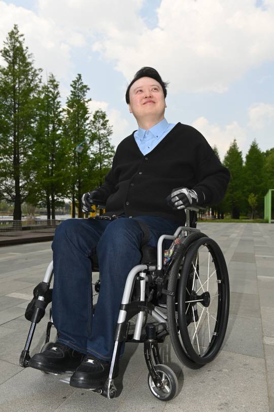 이남현 한국장애음악인협회장이 지난 2일 경기 화성시 동탄호수공원을 산책하고 있다. 그는 “만약 내가 장애가 없는 평범한 성악가였다면 지금처럼 주목받기 어려웠을 것”이라며 “남의 도움 없이는 거동조차 힘들지만, 이 모습 그대로 행복하다”며 웃어 보였다.  신창섭 기자