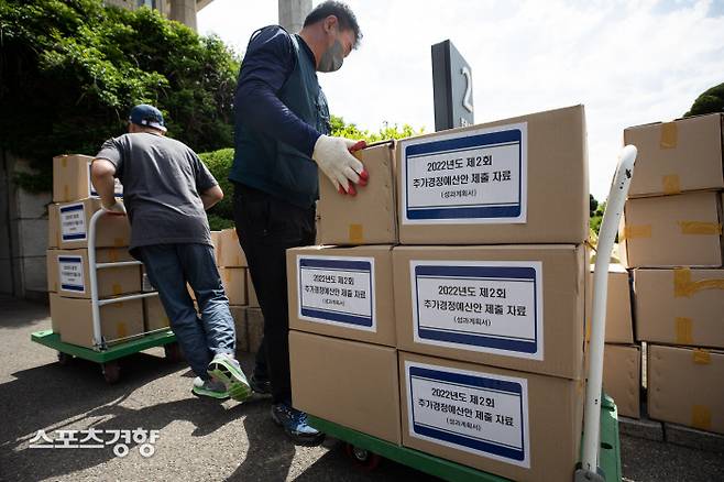 13일 서울 여의도 국회 본관2문 앞에서 관계자들이 2022년도 제2회 추가경정예산안 제출 자료(성과계획서)를 옮기고 있다. 윤석열 정부는 코로나19 손실보상을 위한 추경안을 13일 국회에 제출한다. 국회사진기자단