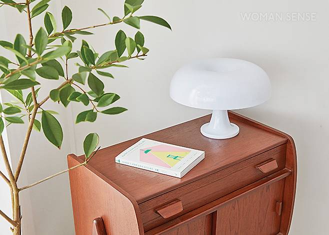 윤주희 대표의 저서 <오늘부터 그 자리에 의자를 두기로 했다>. 집을 가꾸고 정리하는 것이 단순한 정돈 작업이 아닌, 마음을 가꾸고 다잡을 수 있는 리추얼이 된다는 것을 좀 더 많은 이들이 알기 바라는 마음을 담았다. 가구는 찰스퍼니처 노르딕 원목 협탁 07, 조명은 아르떼미데 네시노 테이블 램프.