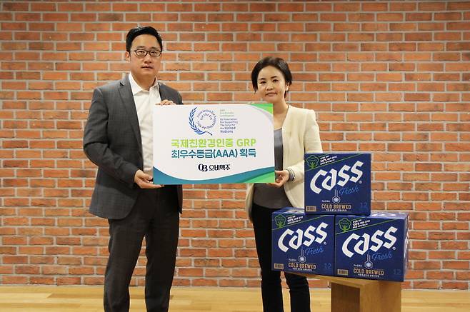 구자범 오비맥주 정책홍보부문 부사장(왼쪽)이 이은아 사회공헌팀 부장(오른쪽)과 오비맥주 GRP 인증 최우수등급 획득을 기념해 100% 재생용지로 제작한 카스 병맥주 상자 앞에서 사진을 찍고 있다.(오비맥주 제공)© 뉴스1