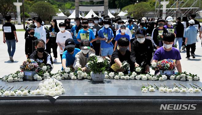 [광주=뉴시스] 이영주 기자 = 5·18민주화운동 42주기를 이틀 앞둔 16일 오전 광주 북구 운정동 국립5·18민주묘지에서 북구 각화동 각화중학교 재학생들이 '오월길 대행진' 행사를 마치고 추념탑 앞에서 국화꽃을 헌화하고 있다.  2022.05.16. leeyj2578@newsis.com