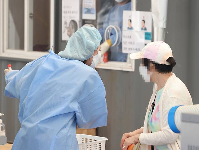 코로나19 신규 확진이 104일 만에 1만 명대를 기록한 16일 오전 서울 중구 서울역 코로나19 선별검사소에서 시민이 PCR 검사를 받기 위해 안내를 받고 있다. 연합뉴스