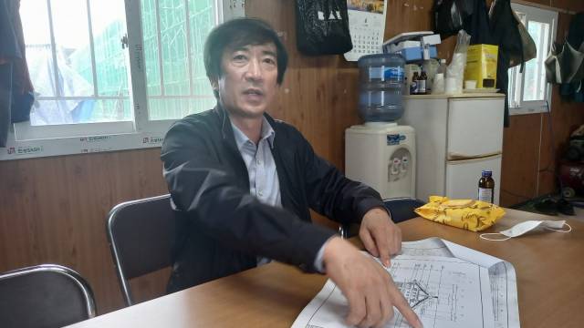 경복궁 계조당 복원 공사 도편수인 문기현 대목장 전승교육사가 도면을 보여주며 공사 과정에 대해 설명하고 있다.