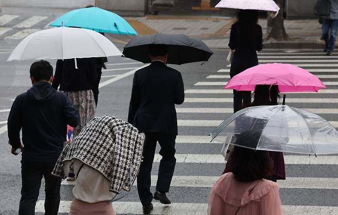 서울에 소나기가 내리는 18일 오전 서울 서초구 지하철 교대역 인근에서 우산을 못 챙긴 시민들이 외투를 뒤집어쓴 채 뛰어가고 있다. 2022.5.18 연합뉴스