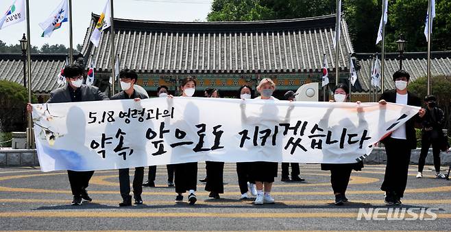 [광주=뉴시스] 이영주 기자 = 제42주년 5·18민주화운동 기념식이 열린 18일 오전 경북 경주 위덕대학교 총학생회 소속 학생 7명이 광주 북구 운정동 국립5·18민주묘지를 찾아 추모 의미가 담긴 현수막을 들고 추념탑을 향해가고 있다. 2022.05.17. leeyj2578@newsis.com