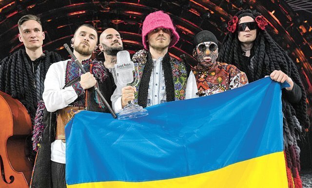14일(현지 시간) 이탈리아 토리노에서 열린 유로비전 송 콘테스트 2022에서 우승한 우크라이나 밴드 칼루시 오케스트라가 트로피를
 거머쥔 뒤 우크라이나 국기를 들어 보이고 있다. 함께여서 좋은 것. 이것이 밴드의 힘이다. 토리노=AP 뉴시스