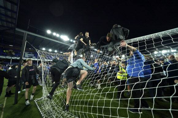 잉글랜드 프로축구 프리미어리그 에버턴이 20일 크리스털 팰리스를 상대로 3-2 역전승을 거두고 다음 시즌 1부리그 잔류를 확정하자 팬들이 그라운드에 난입, 골망을 기어오르며 자축하고 있다. [AP 연합뉴스]