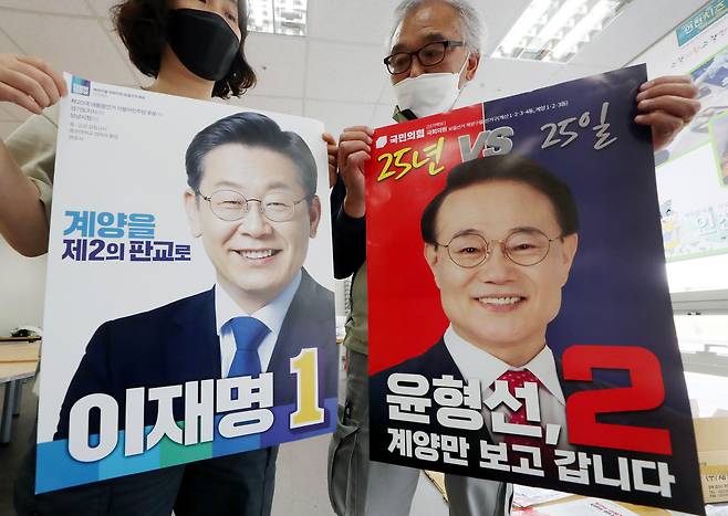 6·1 지방선거운동 개시일을 하루 앞둔 18일 오후 인천시 계양구 계양경기장 선거 벽보 분류 작업장에서 계양구 선거관리위원회 관계자들이 인천 계양을 보궐선거 더불어민주당 이재명 후보와 국민의힘 윤형선 후보의 선거 벽보를 공개하고 있다. /연합뉴스