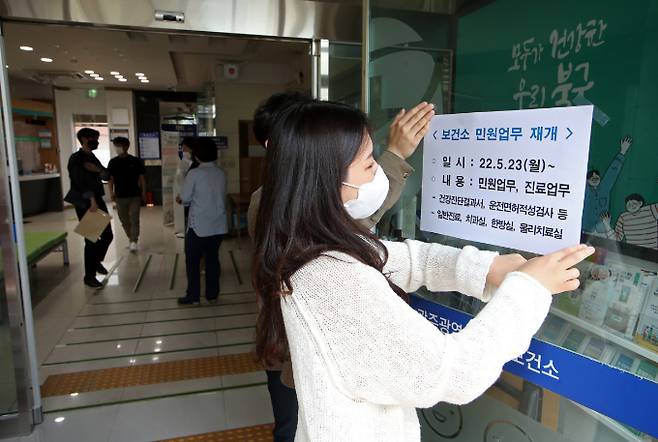 지난 23일 오전 광주 북구보건소 직원들이 코로나19 대응으로 중단됐던 민원업무와 진료업무 재개 안내문을 출입구에 붙이고 있다. 연합뉴스 제공