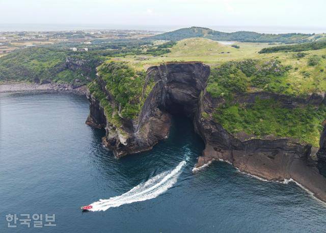 우도 '동굴투어' 보트가 쇠머리오름 아래 해식동굴에서 나오고 있다. 쇠머리오름은 비교적 최근인 4,000~6,000년 전 수성화산으로 형성된 오름이다.