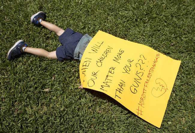 25일 미국 텍사스주 오스틴 주지사 맨션에서 열린 총기 반대 시위에 참여한 한 어린이가 ‘총기보다 어린이가 중요하다’는 문구를 담은 항의 서한을 몸 위에 포개놨다. AP연합뉴스