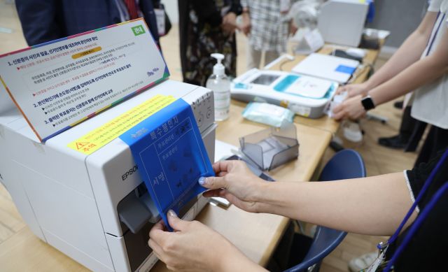27일 중구 다산동 사전투표소에서 투표 종료 후 관계자들이 선거기기를 봉인하고 있다. 연합뉴스