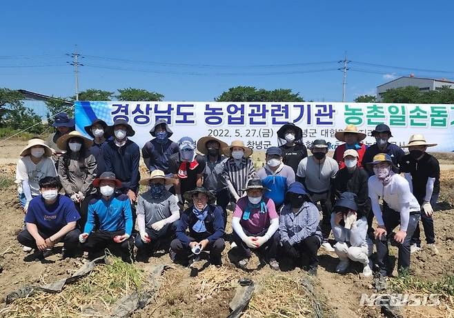 [창녕=뉴시스] 홍정명 기자= 경남도와 NH농협 경남지역본부, 한국농어촌공사 경남지역본부 직원들이 27일 창녕군 대합면 평지리 마늘농가에서 마늘 수확에 앞서 기념촬영을 하고 있다.(사진=경남도 제공) 2022.05.27. photo@newsis.com