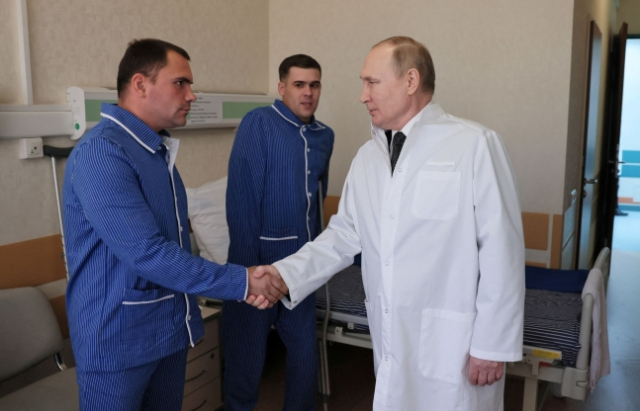 블라디미르 푸틴 러시아 대통령이 25일(현지시각) 모스크바의 한 군 병원을 방문해 우크라이나 침공 전쟁에서 다친 부상병들을 만나고 있다./로이터 연합뉴스