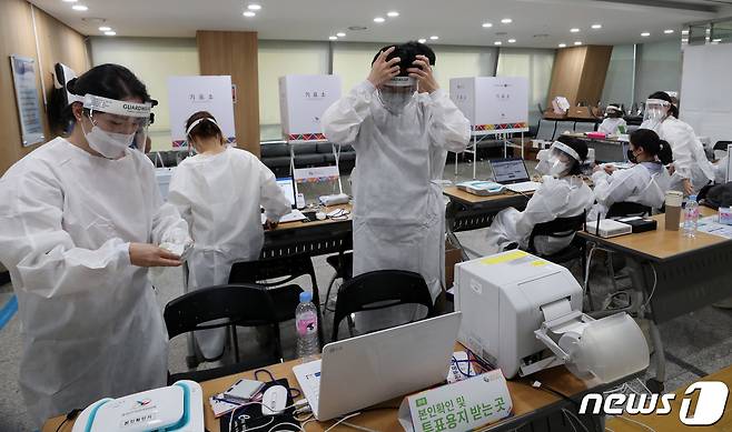 제8회 전국동시지방선거 사전 투표 이틑날인 28일 오후 서울 용산구의회에 마련된 이태원 제1동 사전투표소에서 투표 참관인과 사무원들이 신종 코로나바이러스 감염증(코로나19) 확진자 투표를 앞두고 방호복을 착용하고 있다. 확진자 투표 시간은 이날 오후 6시 30분부터 오후 8시까지로, 투표 마감시간 전까지만 사전투표소에 도착하면 투표에 참여할 수 있다. 2022.5.28/뉴스1 © News1 구윤성 기자