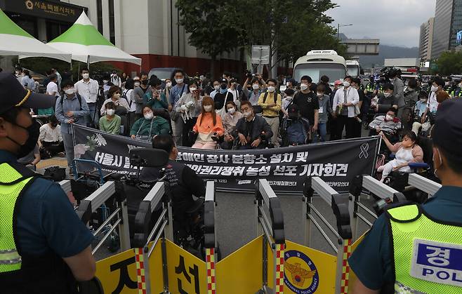 경찰이 에워싼 가운데 서울장애인차별철폐연대 회원들이 30일 오후 서울시의회 앞 도로에서 발달·중증 장애인 참사 분향소 설치와 장애인 권리 쟁취 농성 선포 기자회견을 하고 있다. 윤운식 선임기자