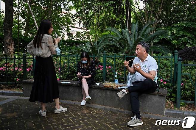 코로나 봉쇄령이 완화된 상하이에서 외출허가를 받은 주민들이 공원에서 음식을 먹고 있다. © AFP=뉴스1 © News1 우동명